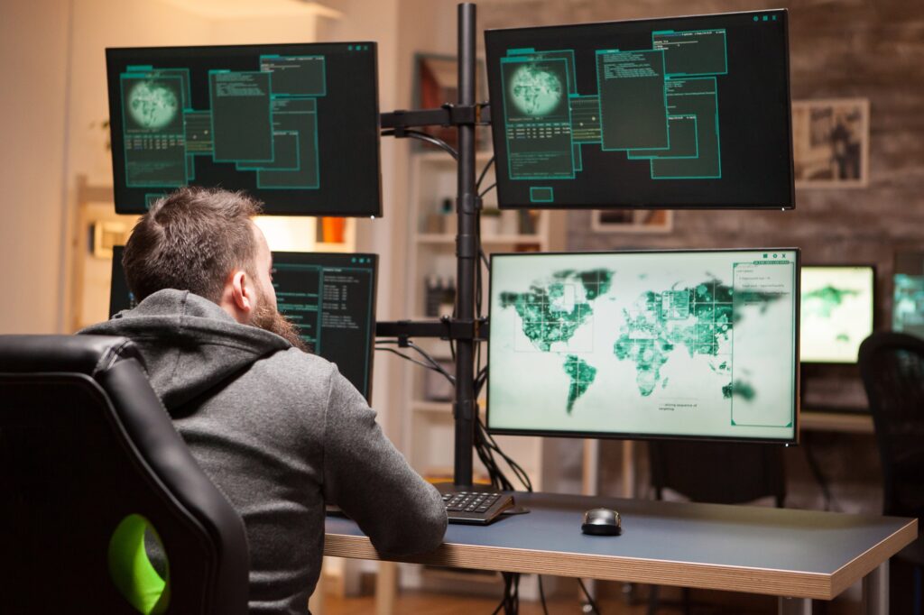 Cybersecurity analyst focused on monitoring global network activity across multiple computer screens, 24/7 Security Monitoring and Threat Detection, Seamless Operations, Optimized Resources, Vulnerability Management and Patching