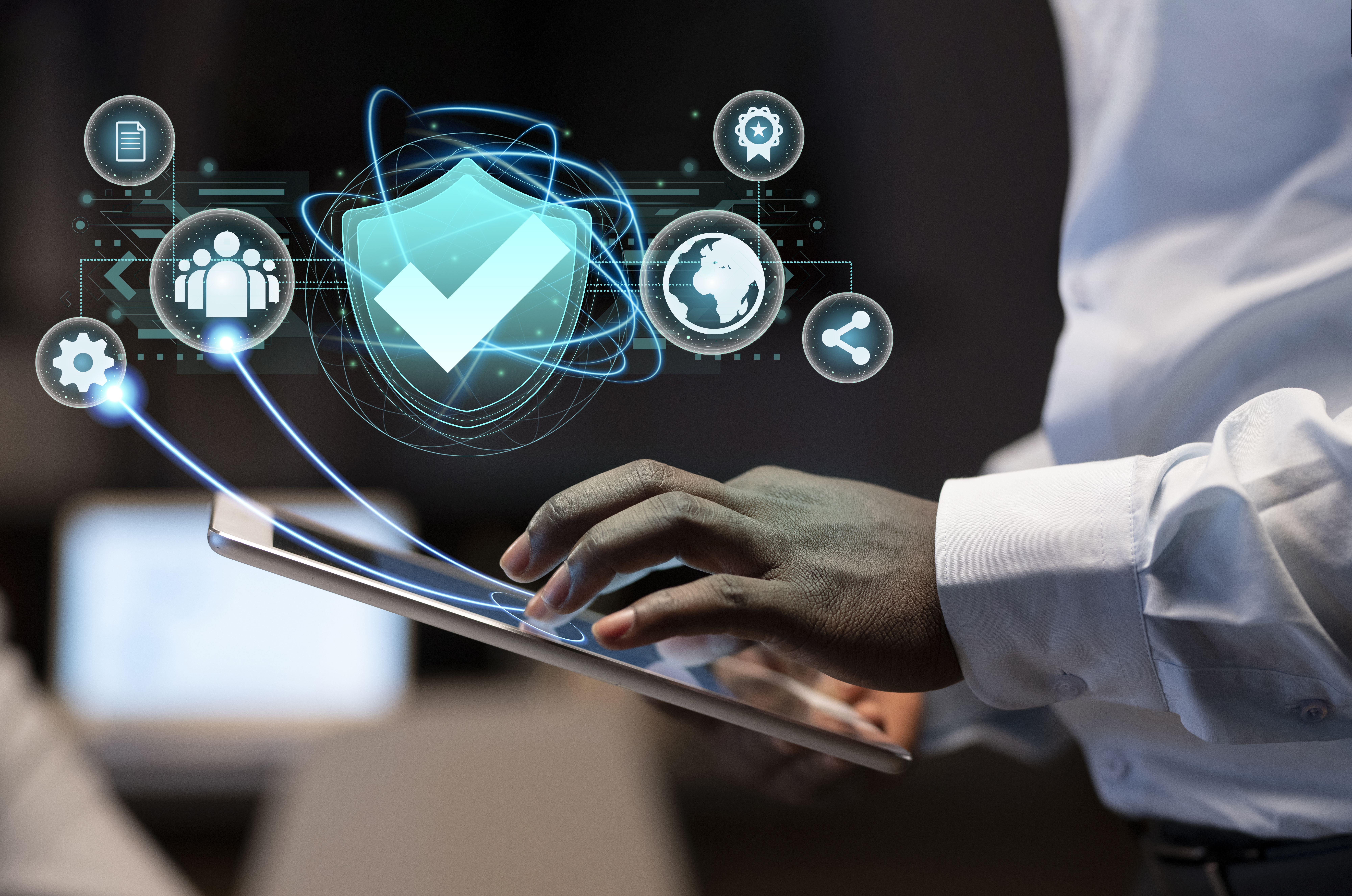 Person using a tablet with futuristic cybersecurity holographic interface hovering above the screen